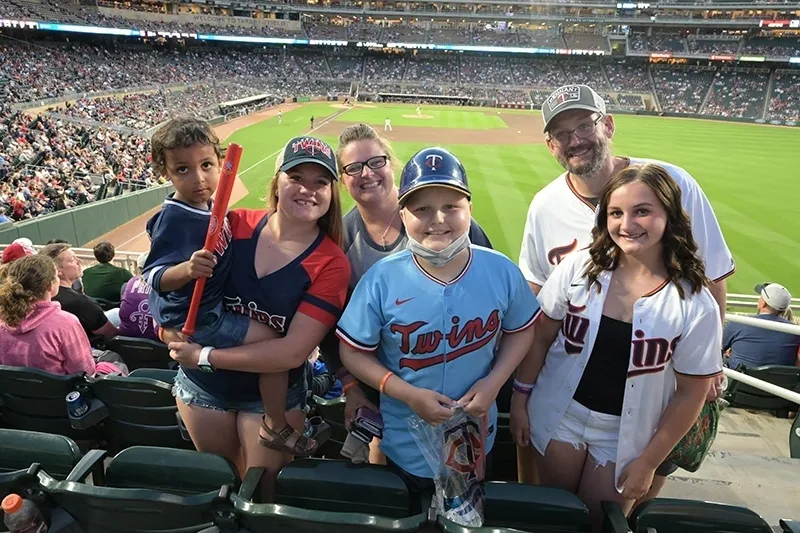 A group of people standing in the stands at a baseball game.