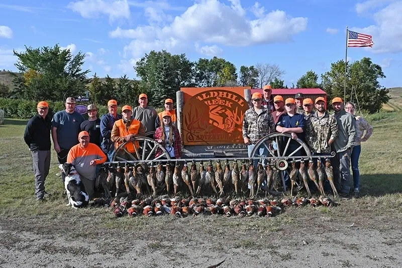 A group of people standing around dead birds.