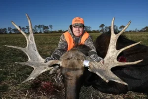A woman in an orange vest with two large antlers.