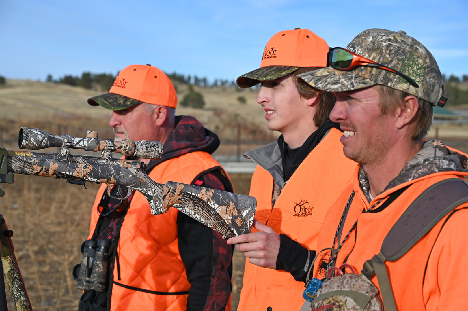A group of men in orange vests holding guns.