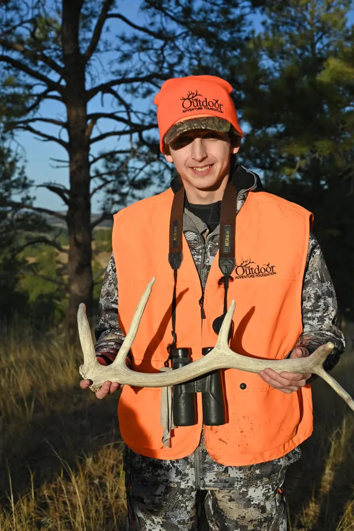 A man holding two large antlers in his hands.