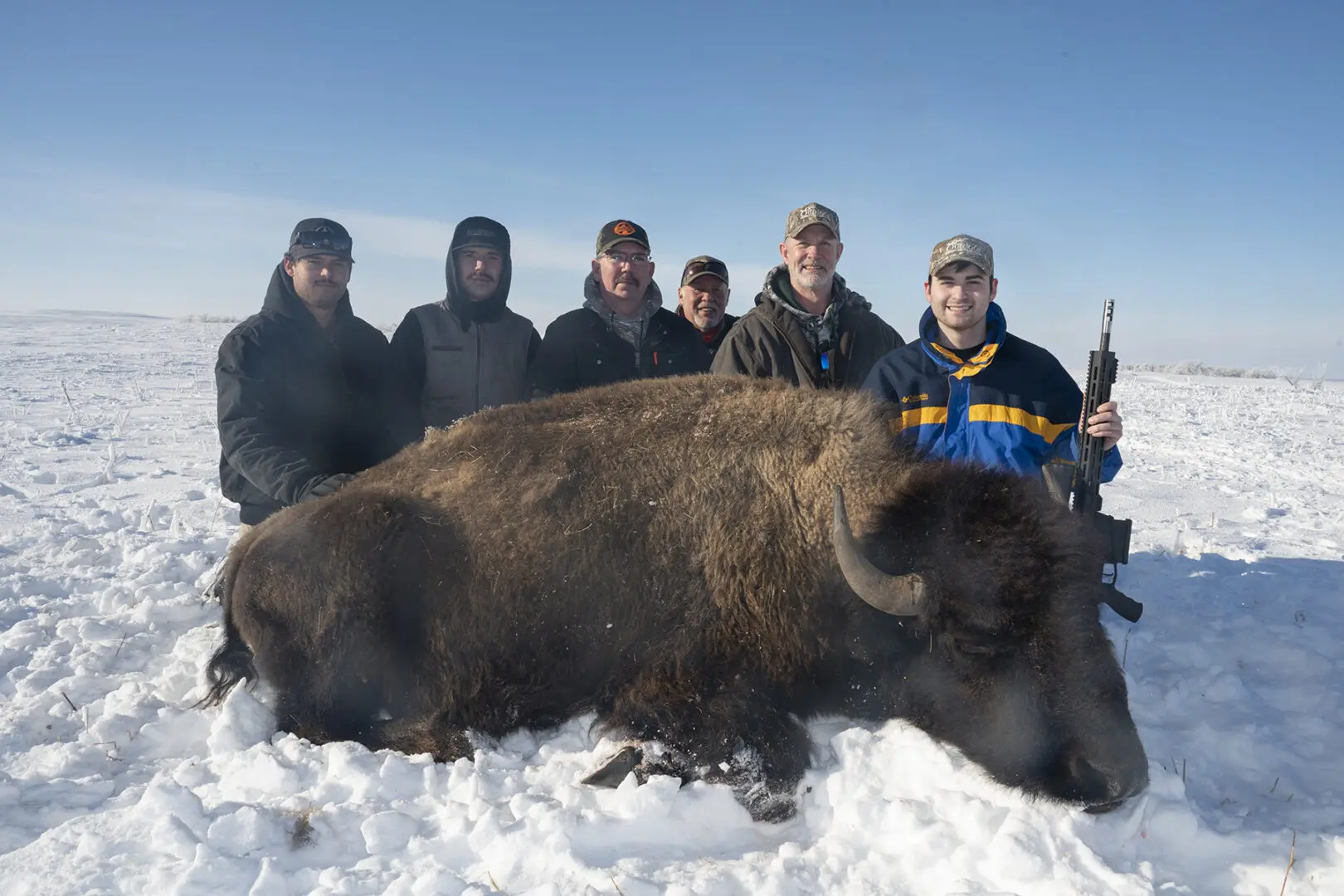 A group of people standing around a bison.