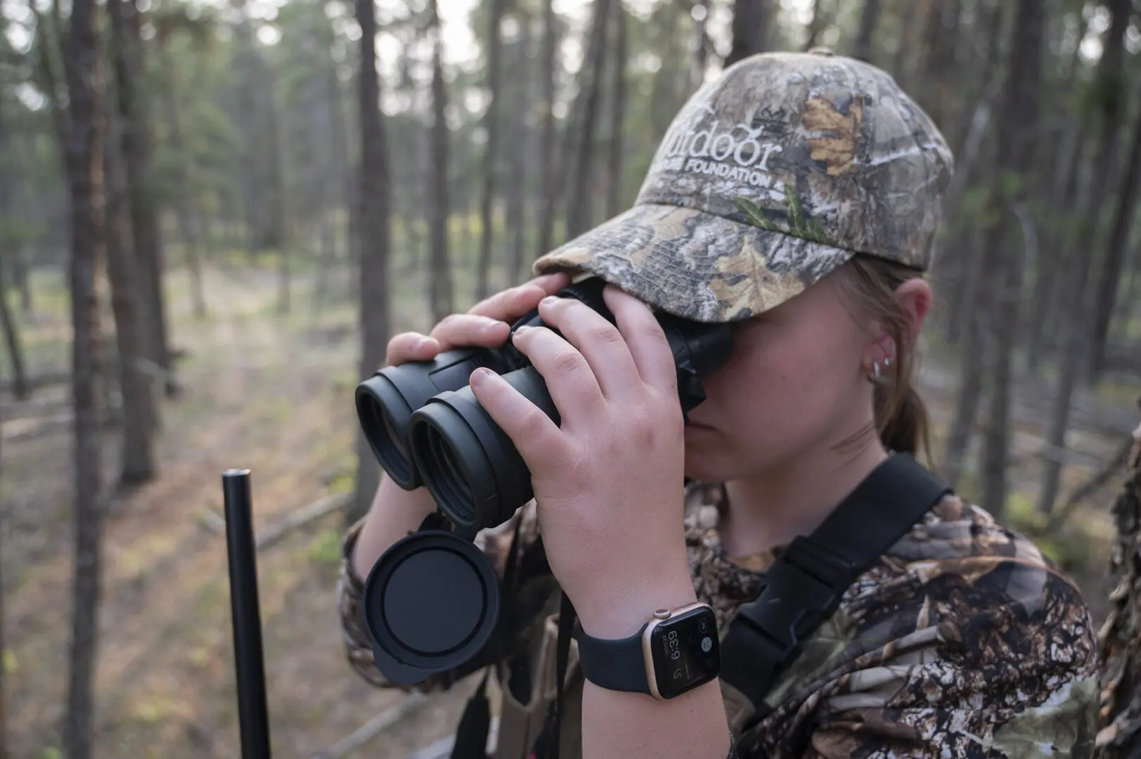 A woman in camouflage looking through binoculars.