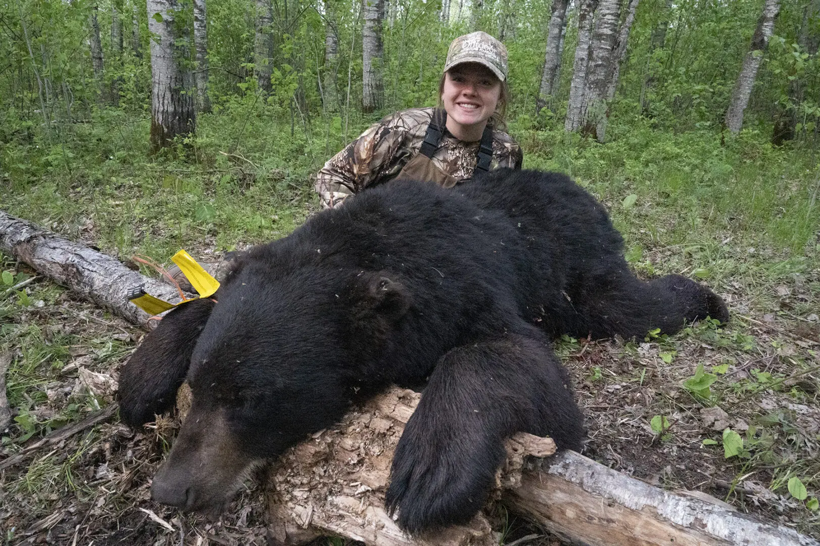 A woman in camouflage holding onto a bear