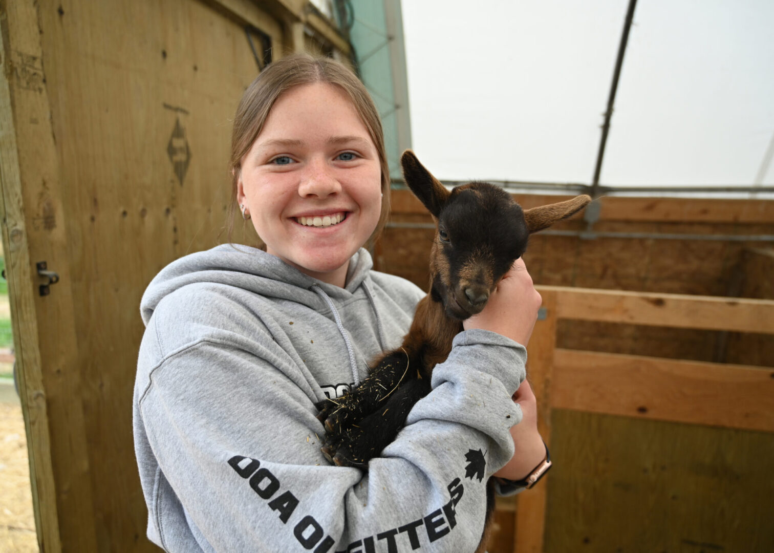 A girl holding a baby goat in her arms.