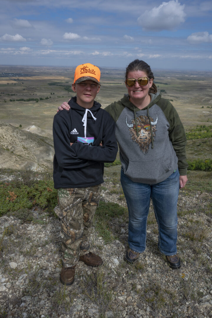 Two people standing on a hill with one of them wearing an orange hat.
