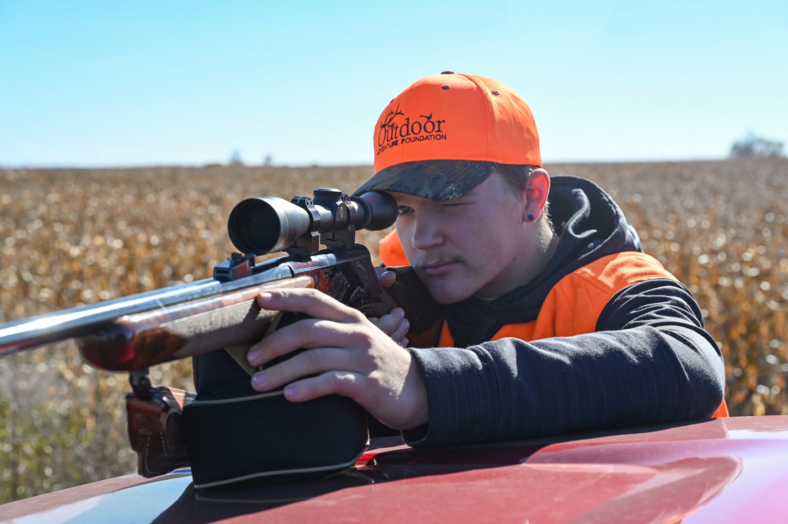 Case Thompson takes aim with his rifle over the hood of a pickup.