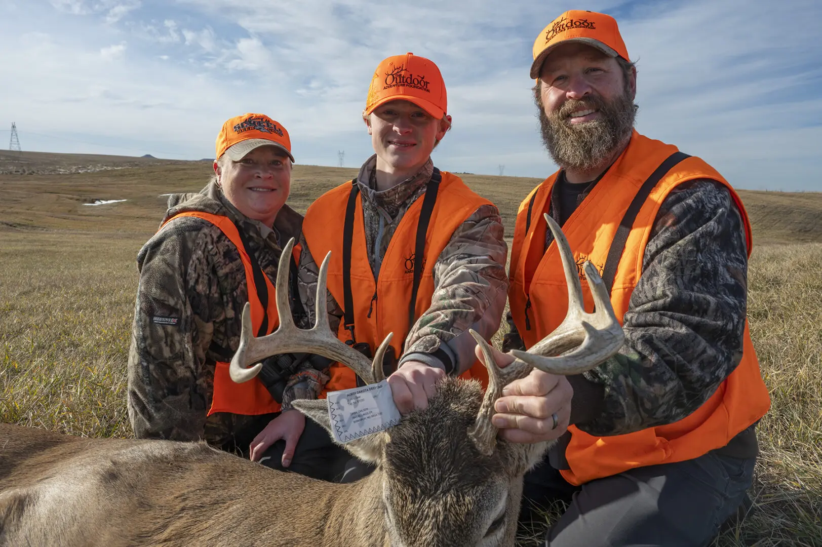 From left to right Kara Ohlsen, Dash Ohlsen and Taner Ohlsen pose with Dash's white-tailed buck