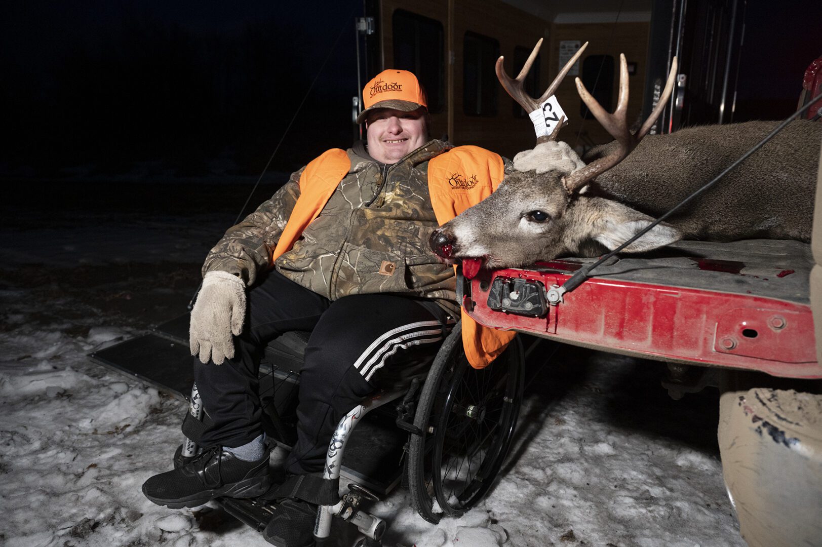 A man in a wheelchair with a deer.