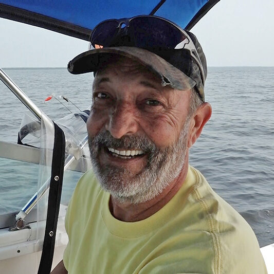 A man in yellow shirt and hat on boat.
